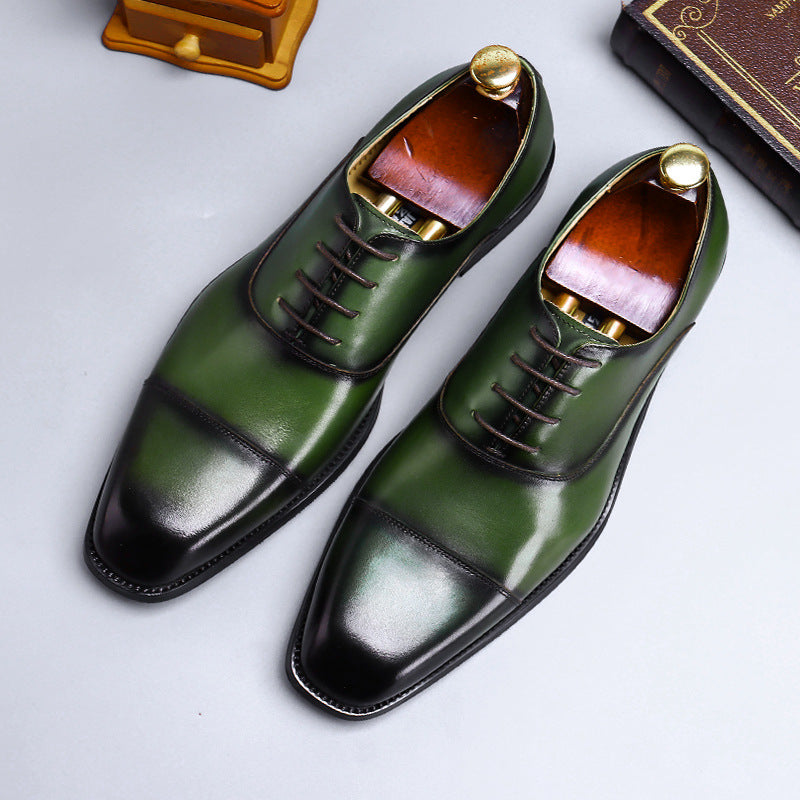 Green leather dress shoes with black soles on a light gray background