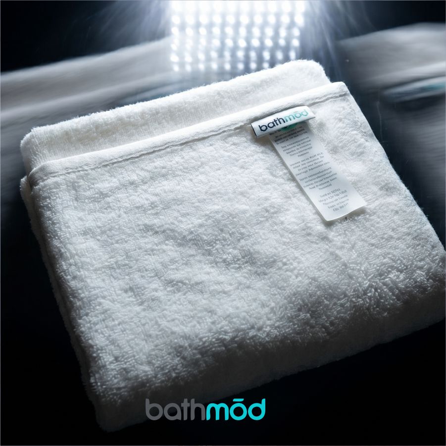Folded white towel with 'bathmod' label on a dark background