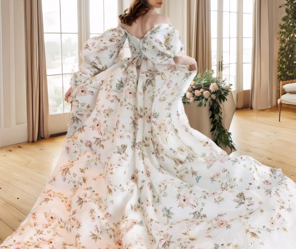 Woman in a floral dress standing in a room with large windows and decorative plants.