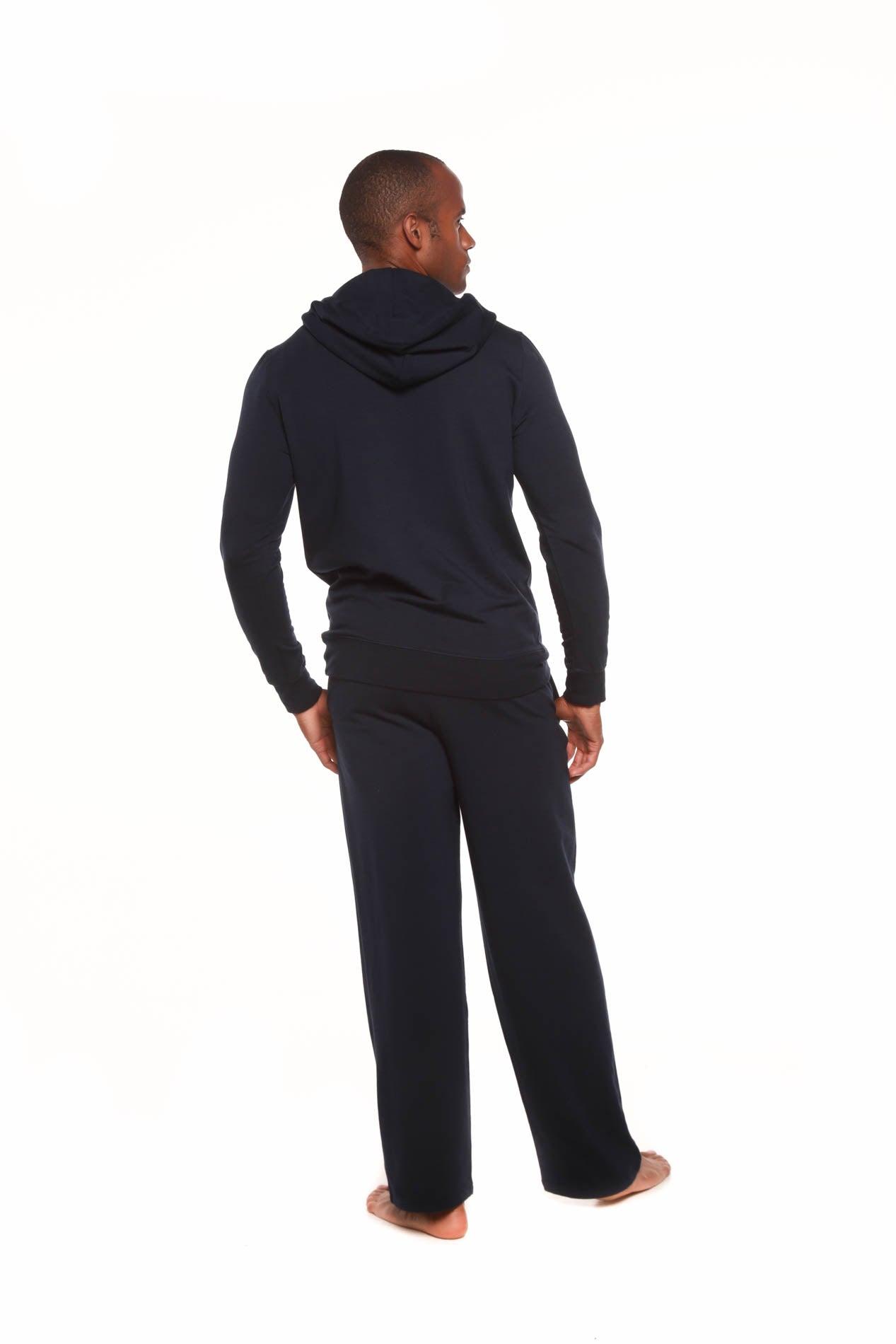 Person wearing a black hoodie and pants on a white background