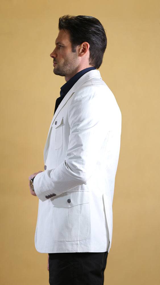 Man wearing a white blazer over a black shirt on a beige background