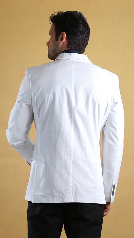 Man wearing a white blazer against a beige background