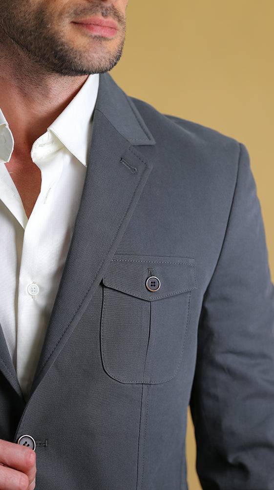 Gray blazer worn by a person with a white shirt underneath, against a beige background