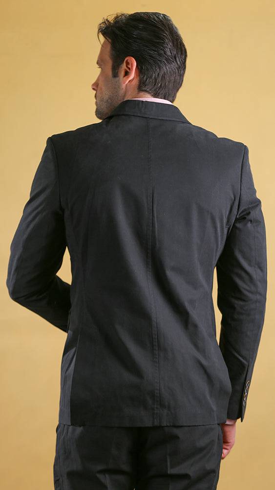 Man wearing a black suit jacket against a beige background