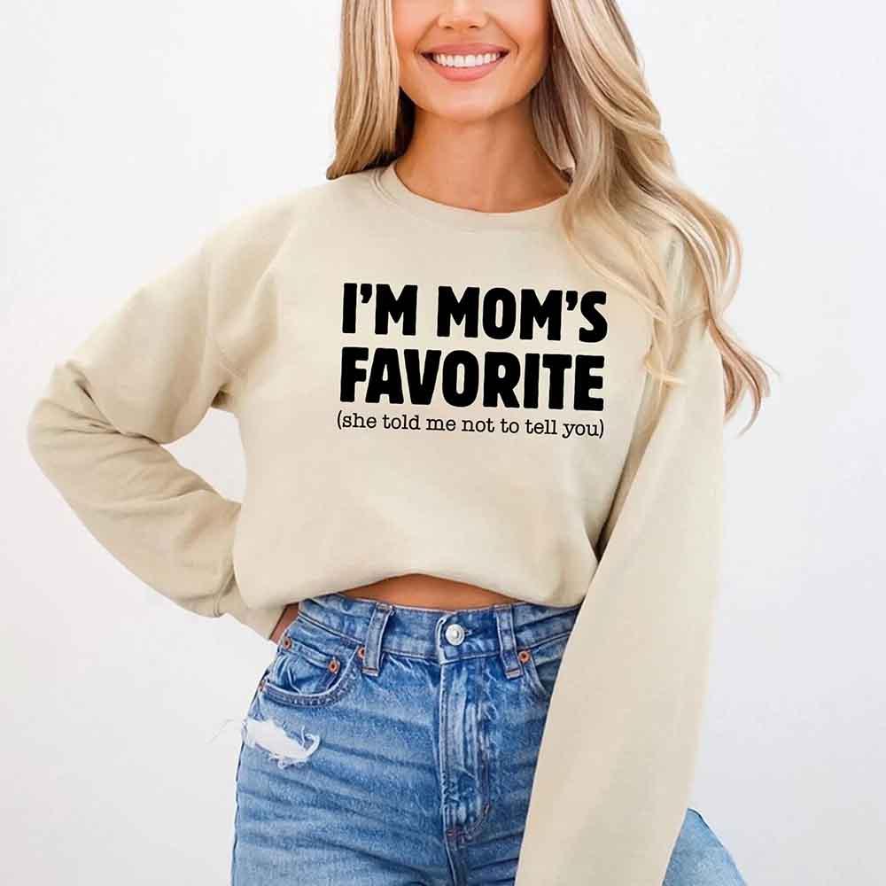 Person wearing a beige sweatshirt with text and blue jeans on a white background