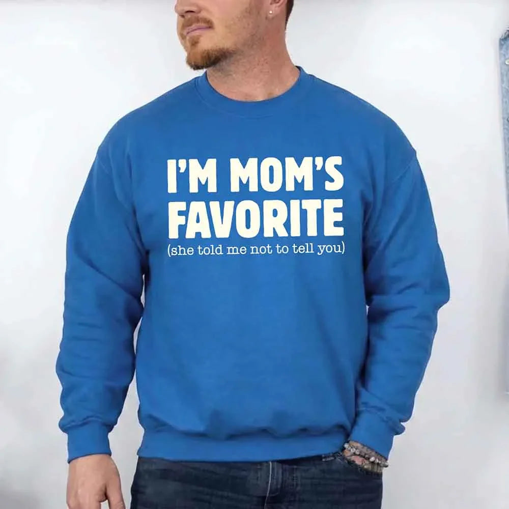 Person wearing a blue sweatshirt with text 'I'M MOM'S FAVORITE (she told me not to tell you)' against a white background