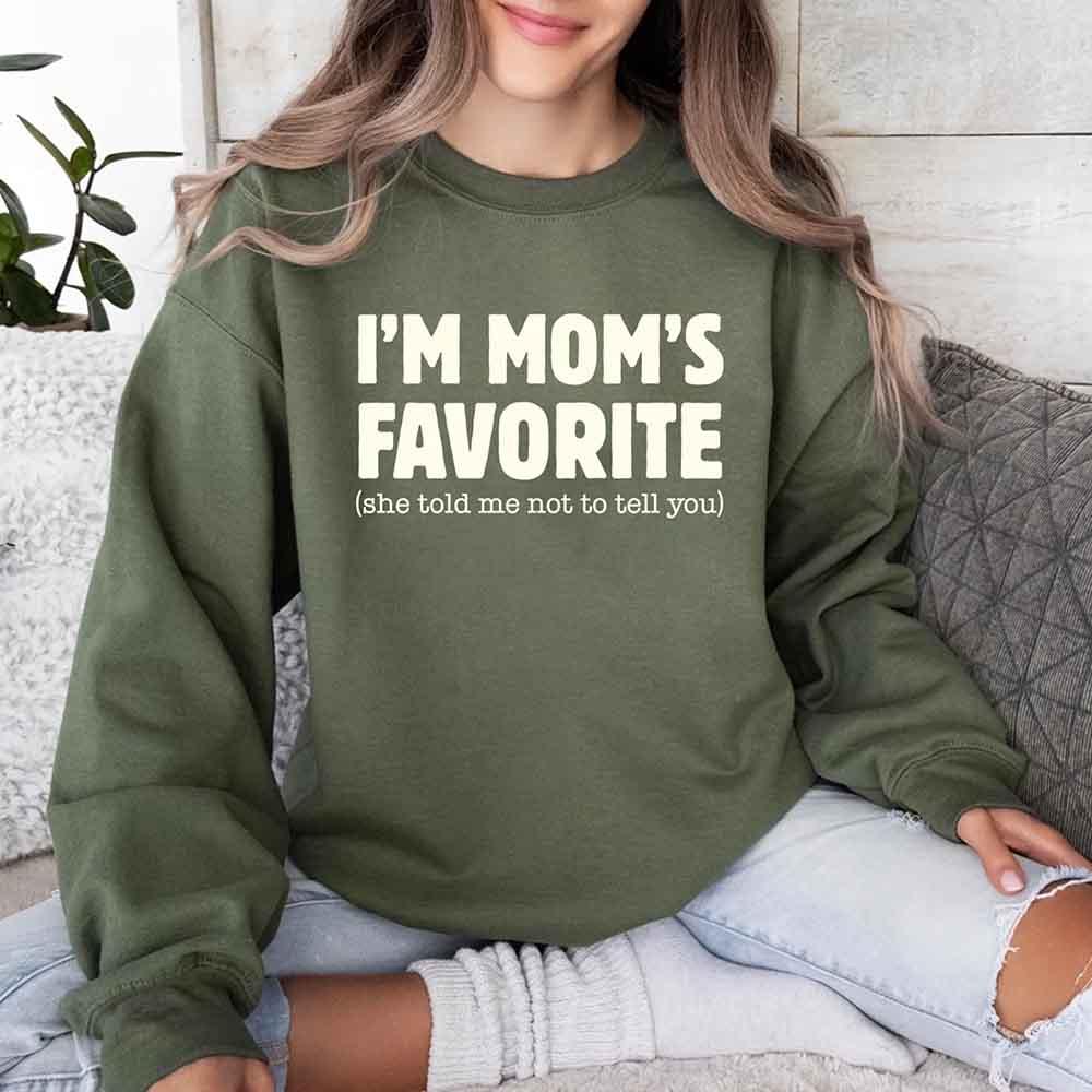 Person wearing a green sweatshirt with text sitting on a couch.