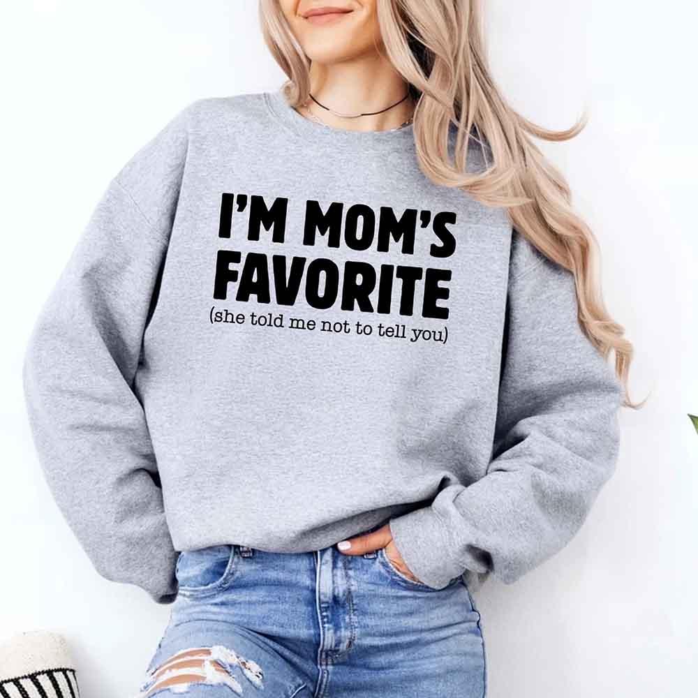 Person wearing a gray sweatshirt with 'I'm Mom's Favorite (she told me not to tell you)' text.