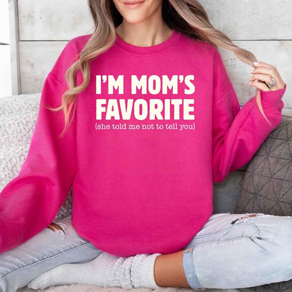 Person wearing a pink sweatshirt with text sitting on a couch.