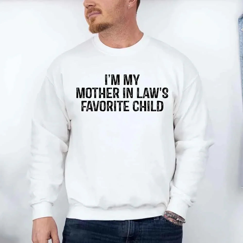 Person wearing a white sweatshirt with text 'I'm my mother-in-law's favorite child' on a plain background