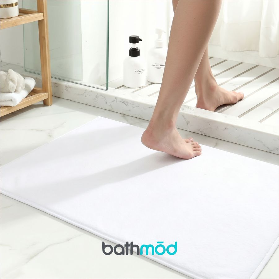 Person stepping onto a white bath mat with 'bathmod' branding in a bathroom setting.