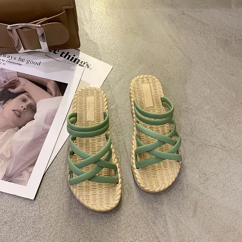 Pair of green sandals with woven straps on a textured surface next to a magazine.
