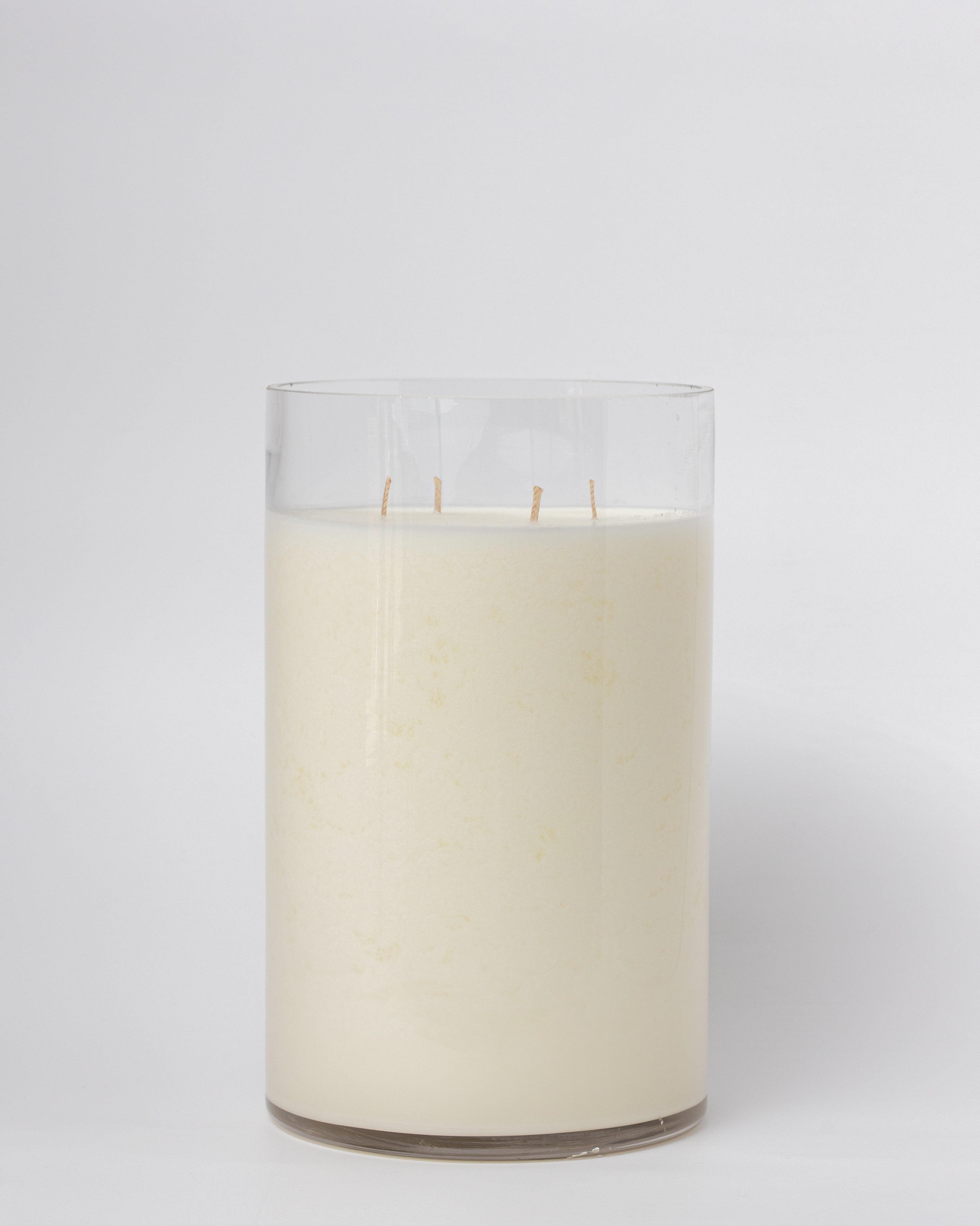 White candle in a clear glass container on a white background