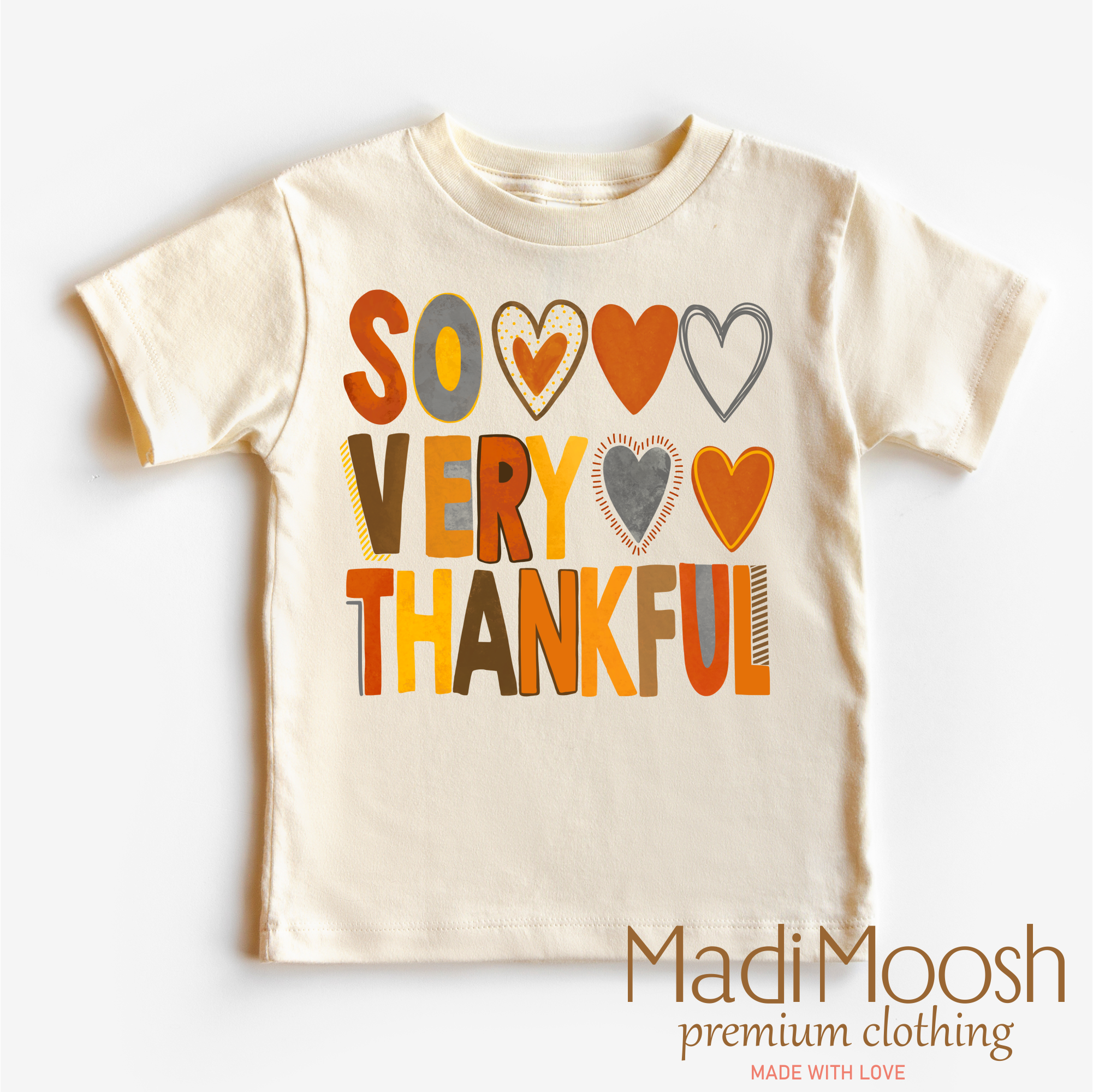 Beige t-shirt with colorful text 'SO VERY THANKFUL' and hearts on a white background, branded as Madi Moosh.