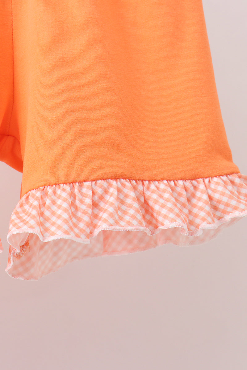 Orange dress with a ruffled hem on a light gray background