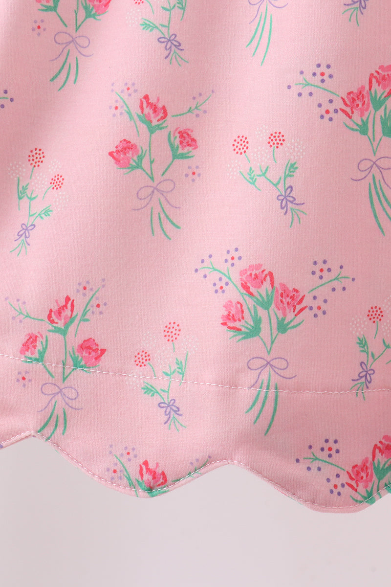 Floral pattern on a pink fabric with green leaves and red flowers.