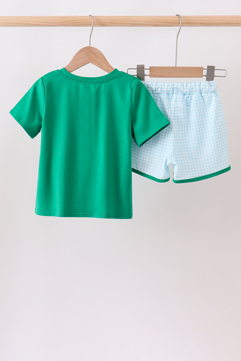 Green t-shirt and checkered shorts on hangers against a white background