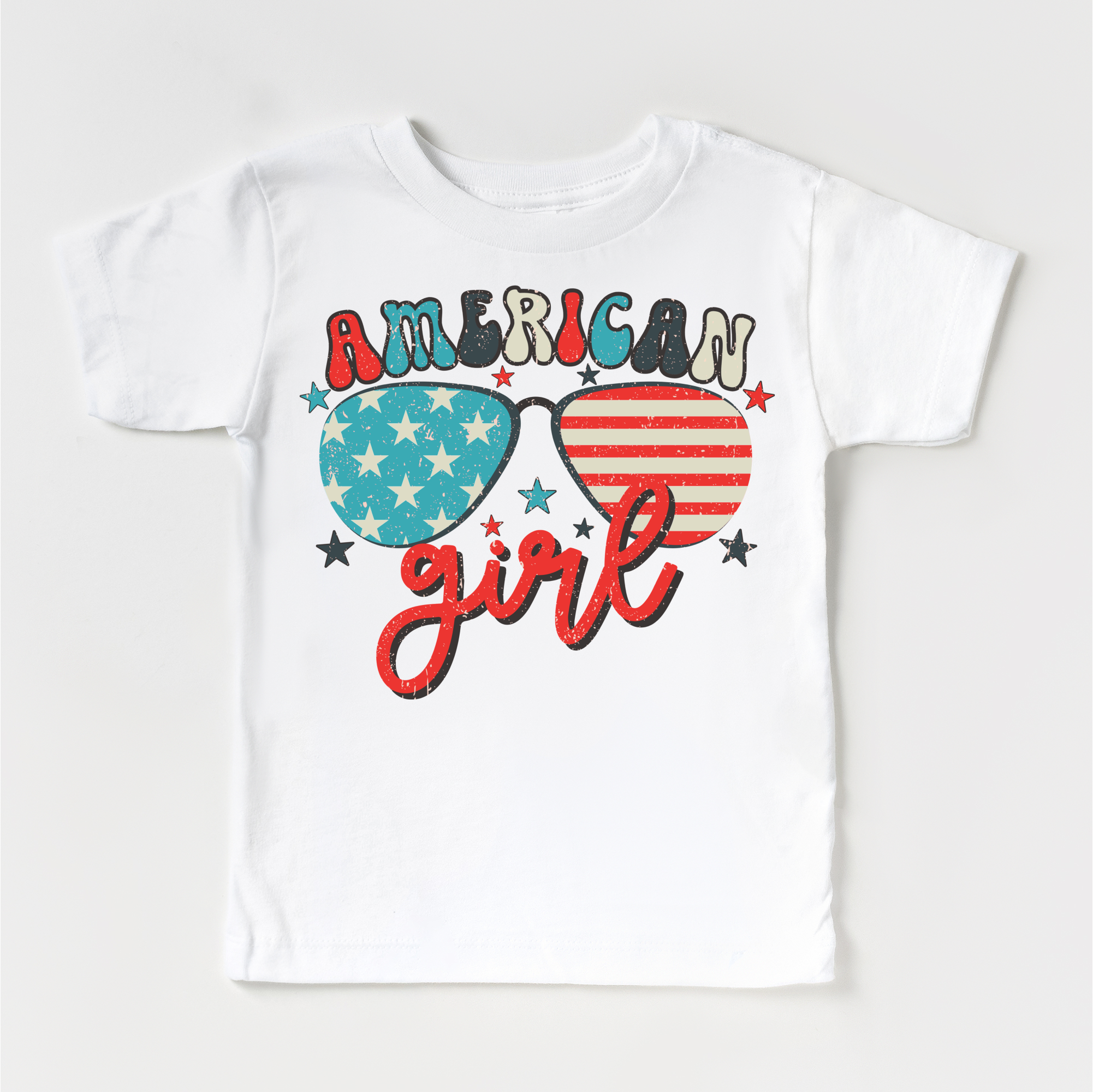 White t-shirt with 'American Girl' design featuring sunglasses with American flag and star patterns on a white background.
