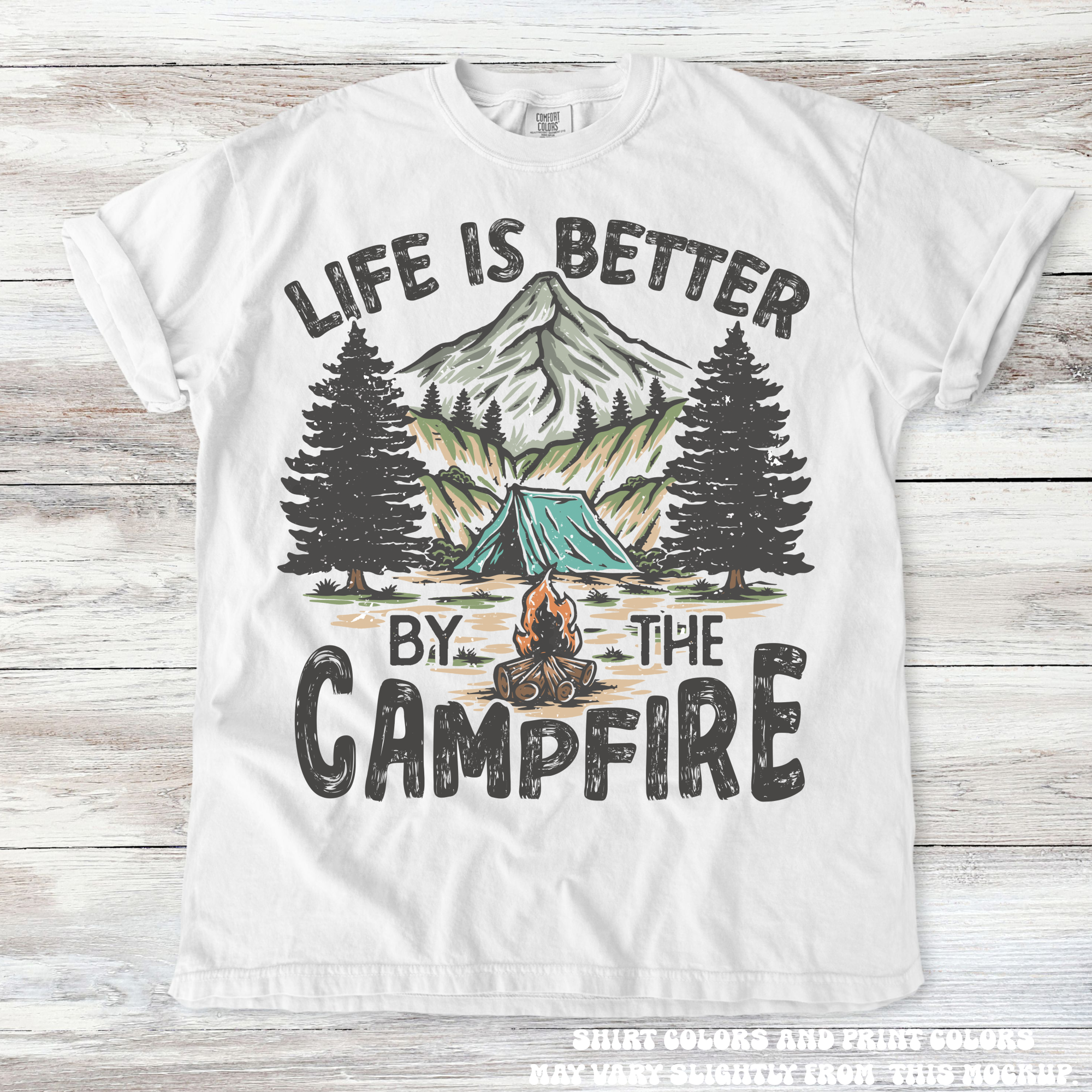 White t-shirt with camping graphic and 'Life is Better by the Campfire' text on a wooden background
