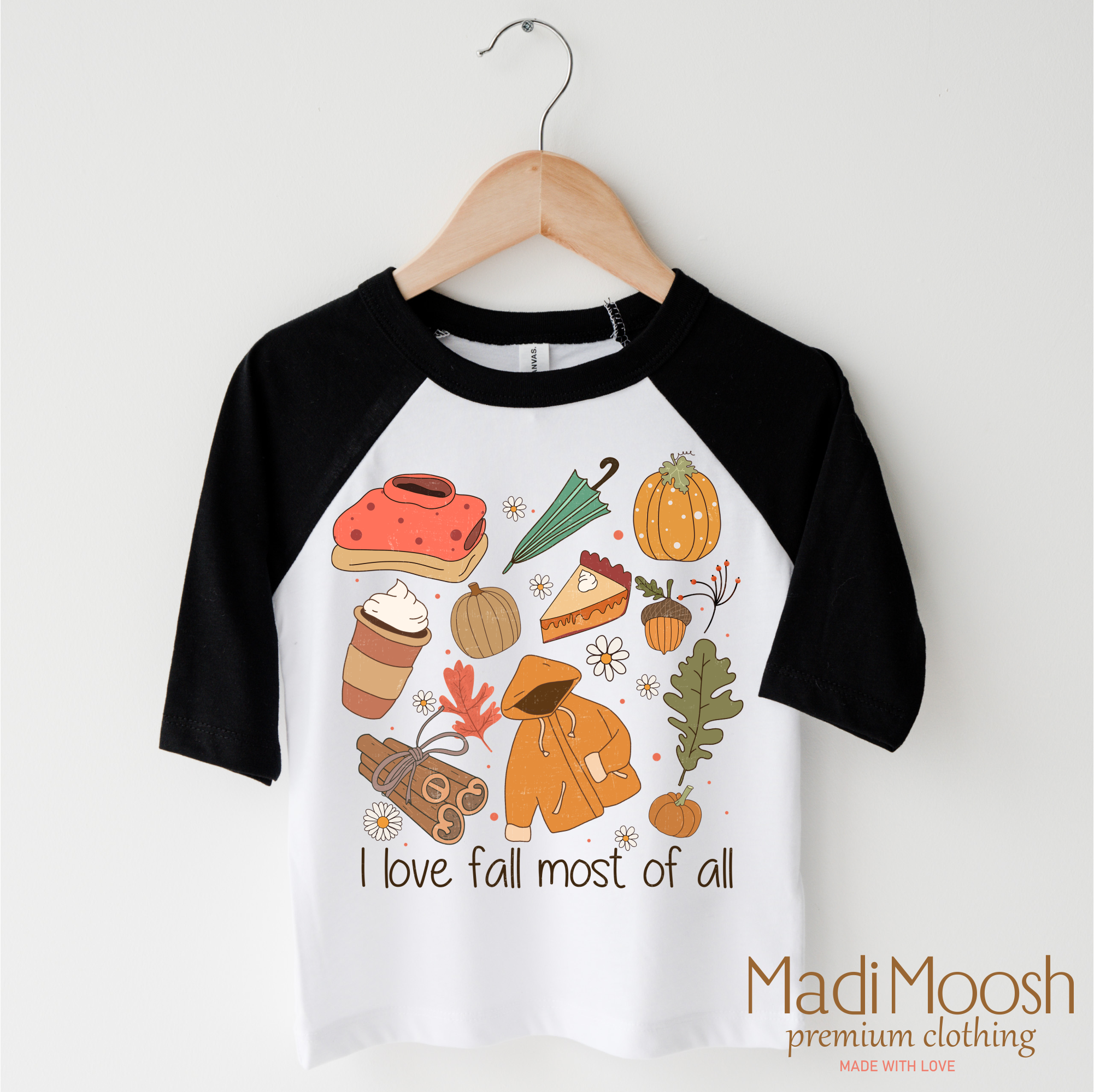 Children's black and white 3/4 sleeve raglan shirt with autumn-themed graphics and text on a hanger.
