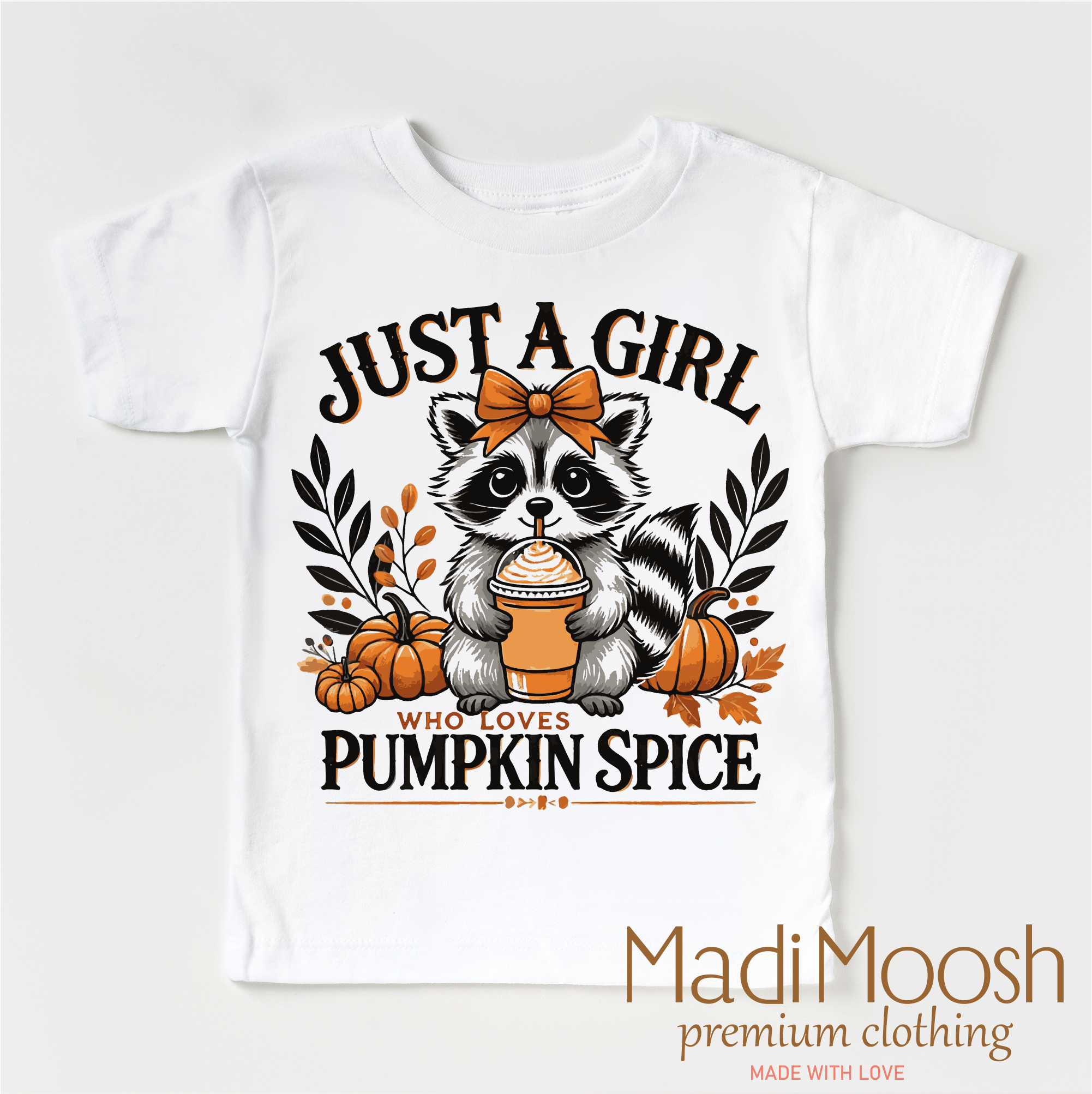 White t-shirt with a raccoon graphic and text 'Just a girl who loves pumpkin spice' on a white background, featuring the brand 'Madi Moosh'.