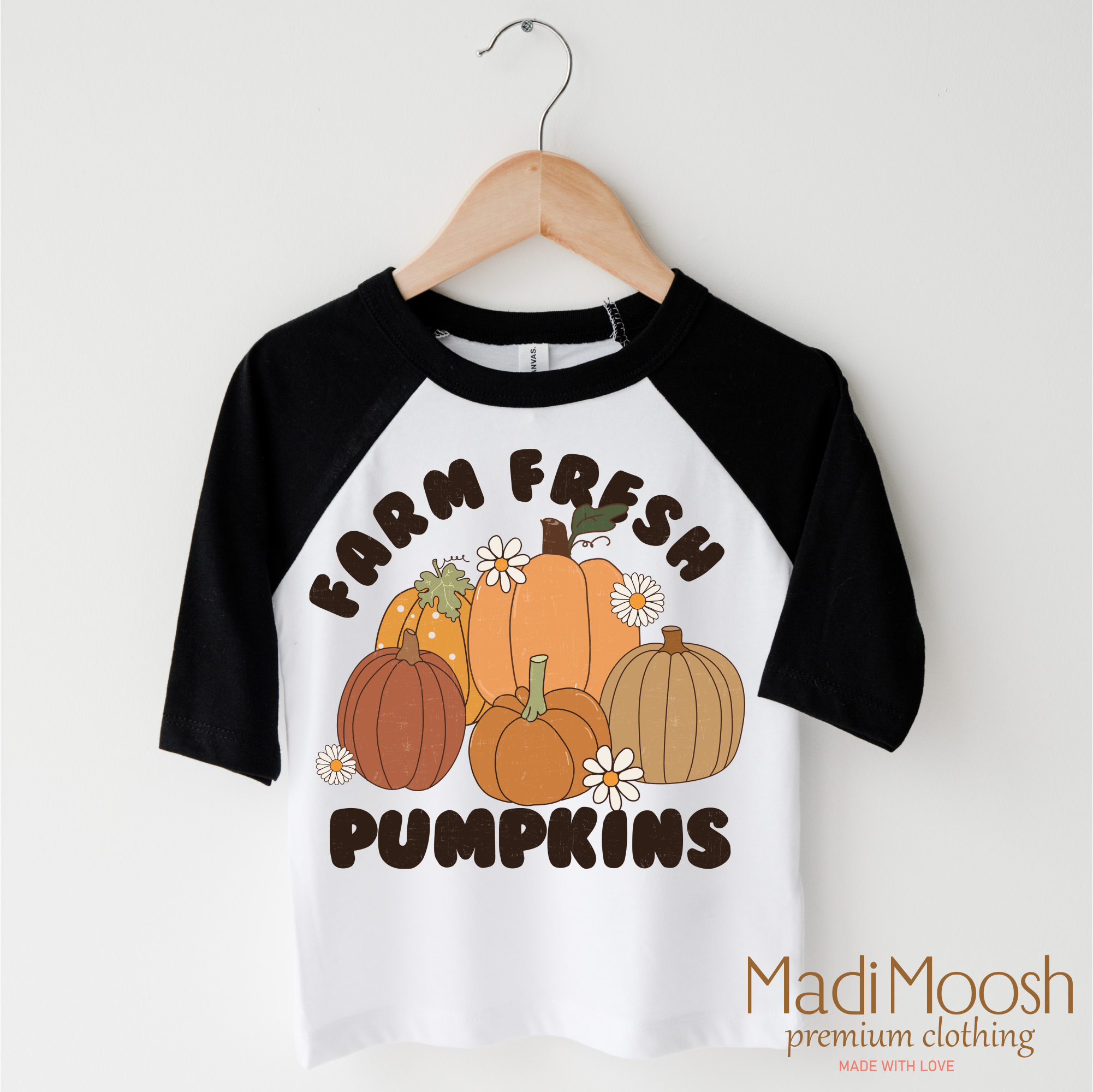 Children's 3/4 sleeve shirt with 'Farm Fresh Pumpkins' design on a hanger, brand 'Madi Moosh' visible.
