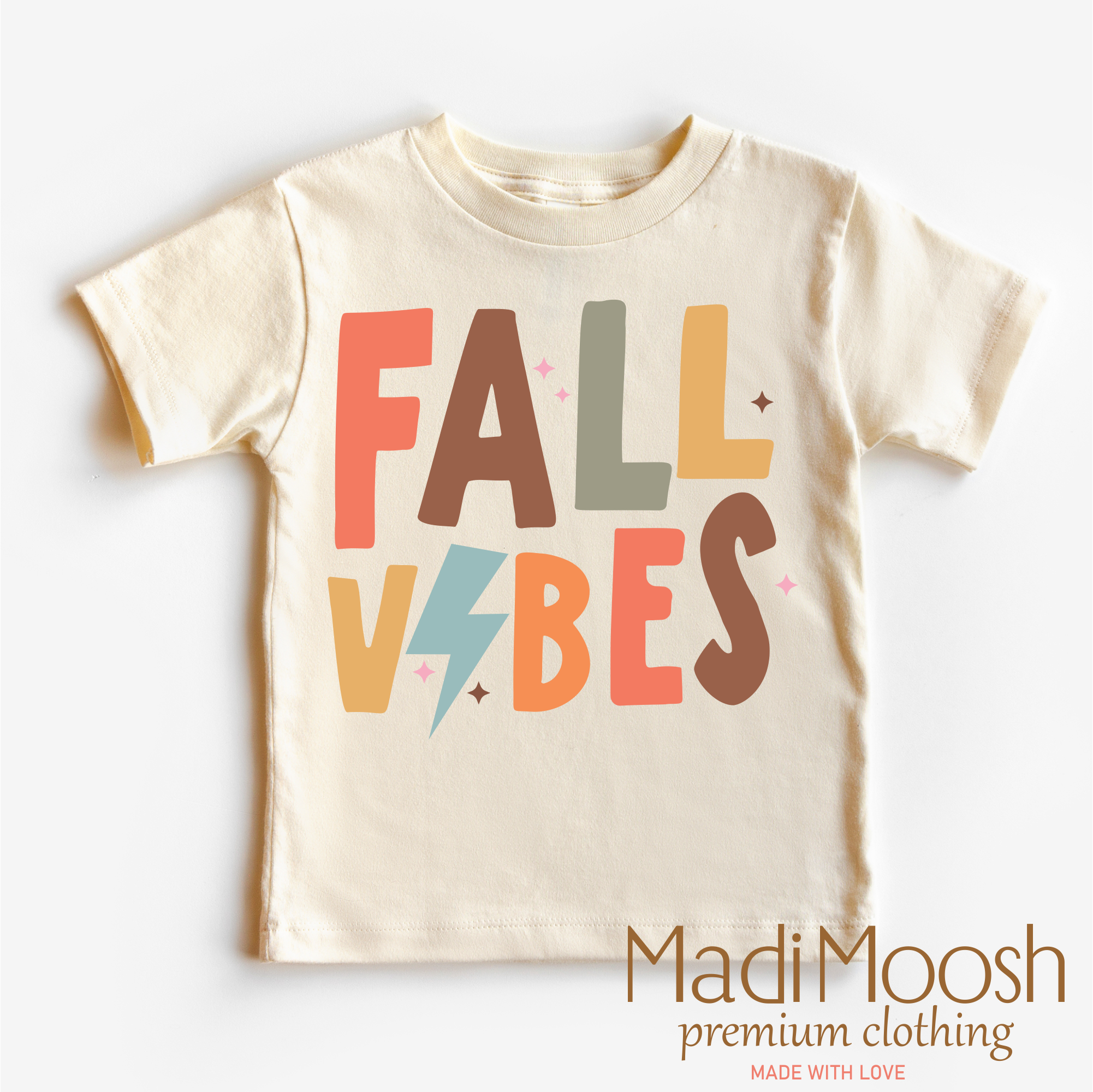 Beige t-shirt with 'Fall Vibes' text in colorful letters on a white background, branded as Madi Moosh.
