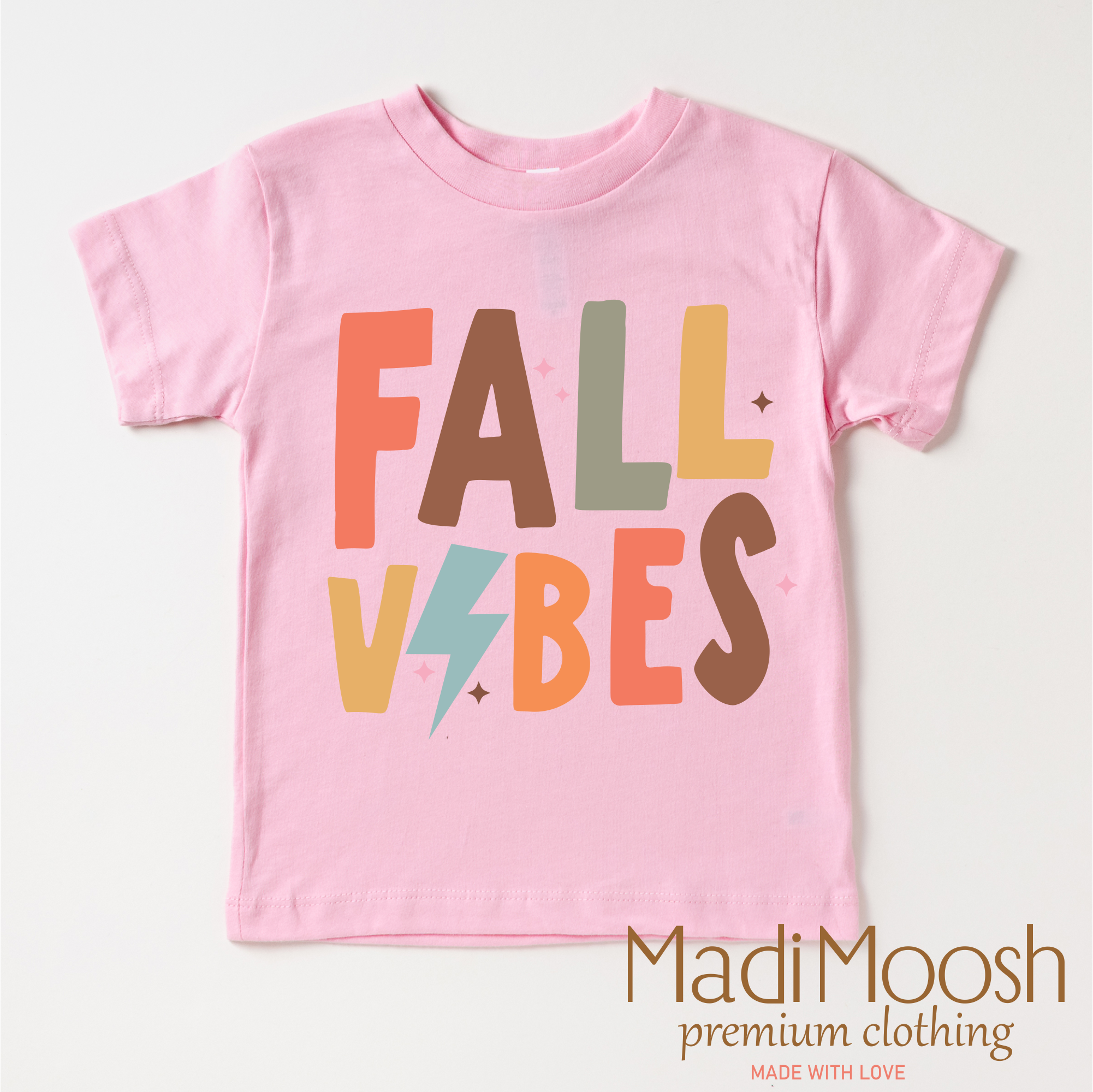 Pink t-shirt with 'Fall Vibes' text on a white background, featuring the brand 'Madi Moosh'.