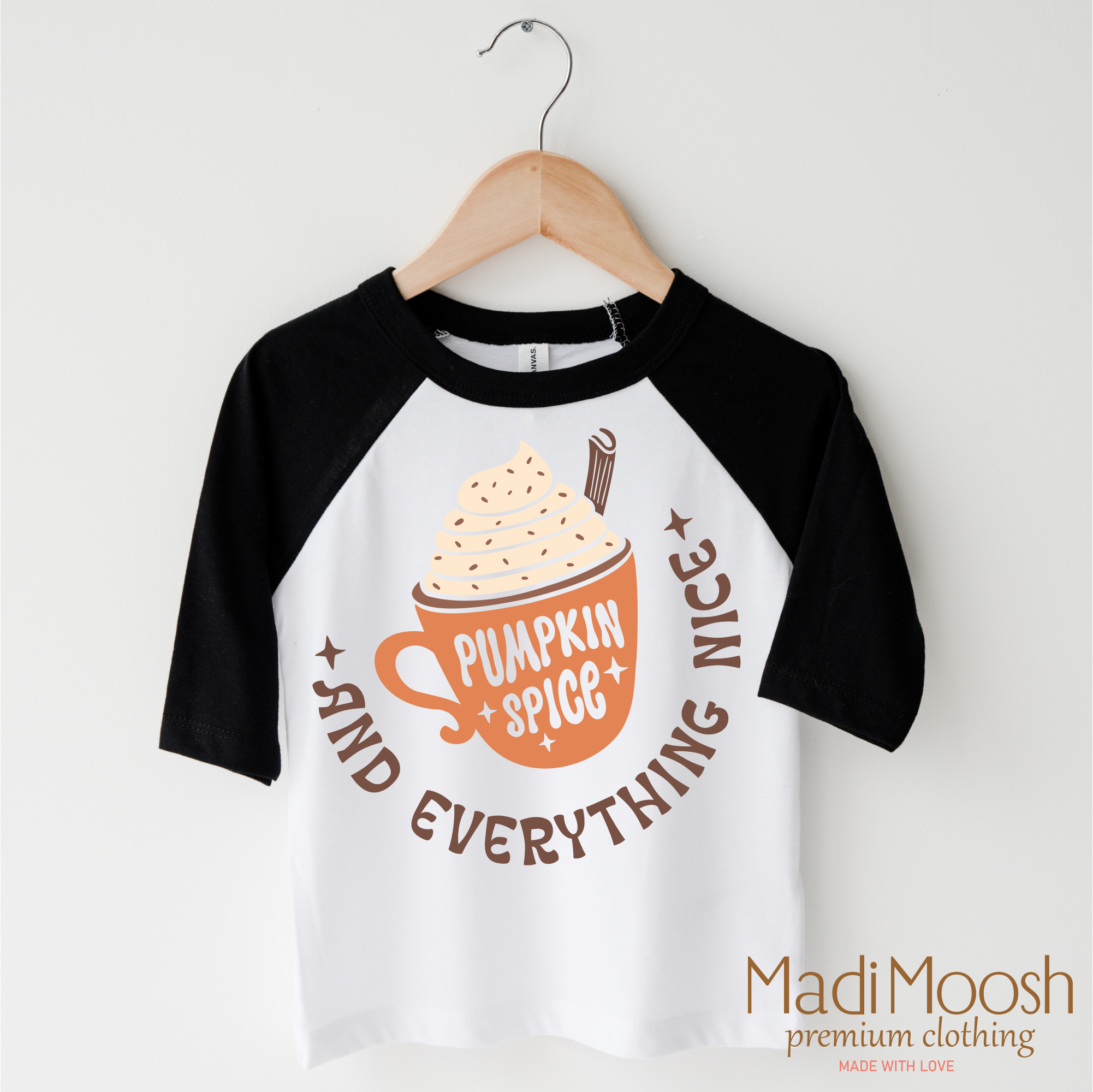 Children's 3/4 sleeve shirt with pumpkin spice design on a hanger, featuring the brand 'Madi Moosh'.