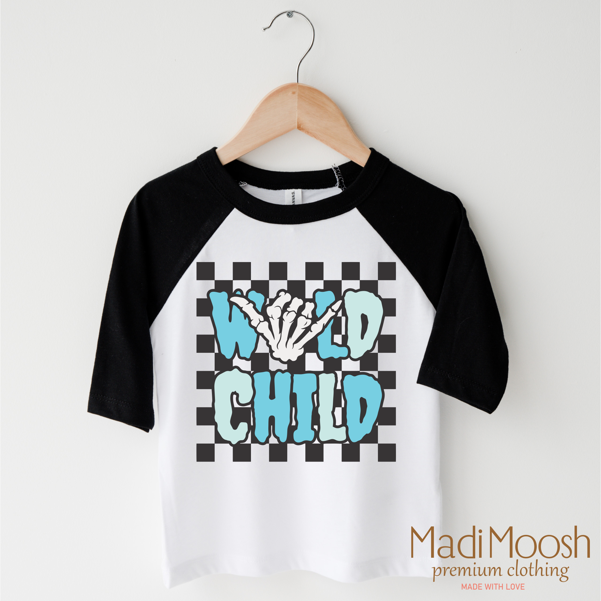 Black and white baseball 3/4 sleeve shirt with 'Wild Child' design on a hanger, branded 'Madi Moosh'.