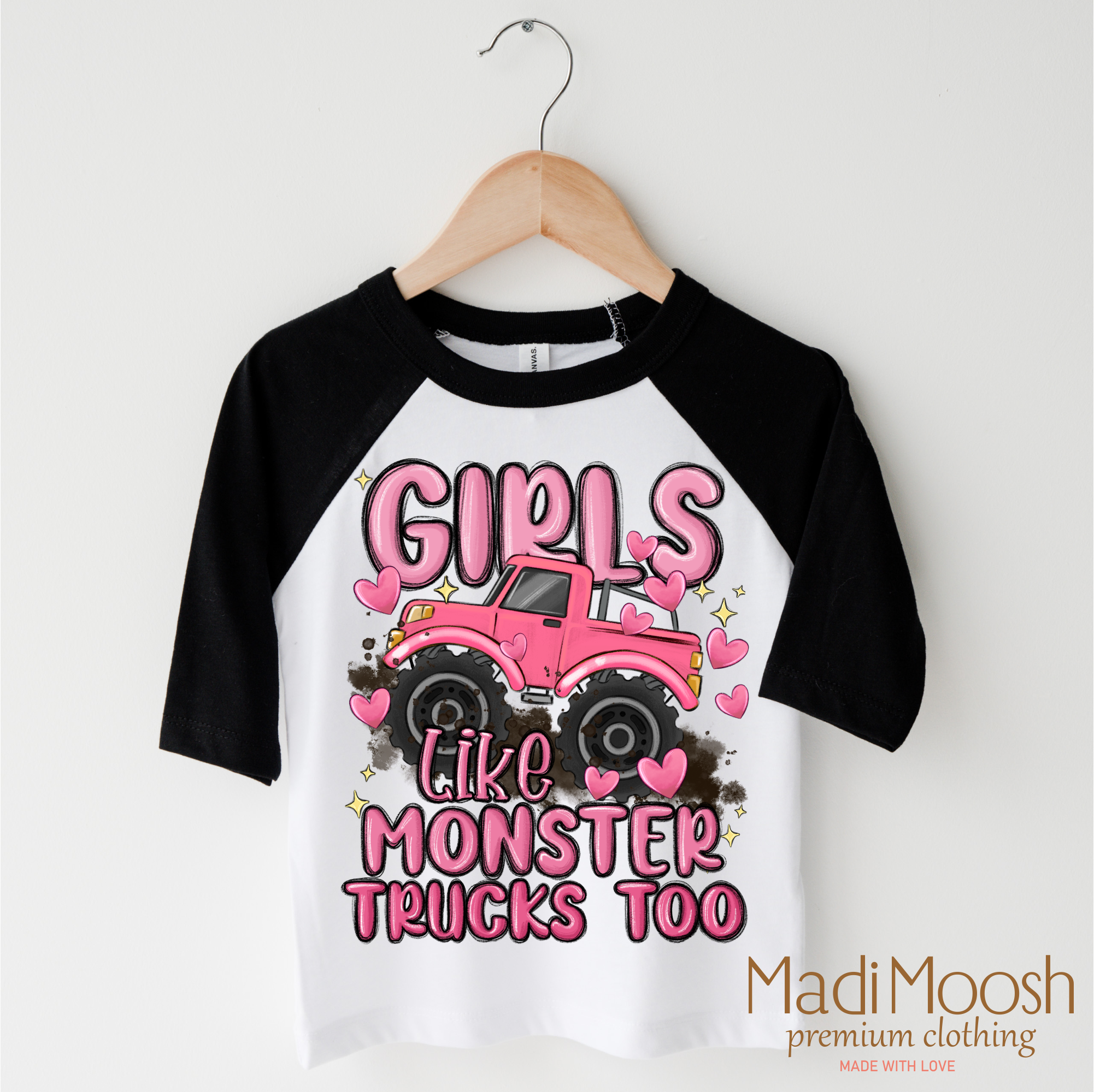 Black and white baseball 3/4 sleeve shirt with pink monster truck graphic and text on a hanger.