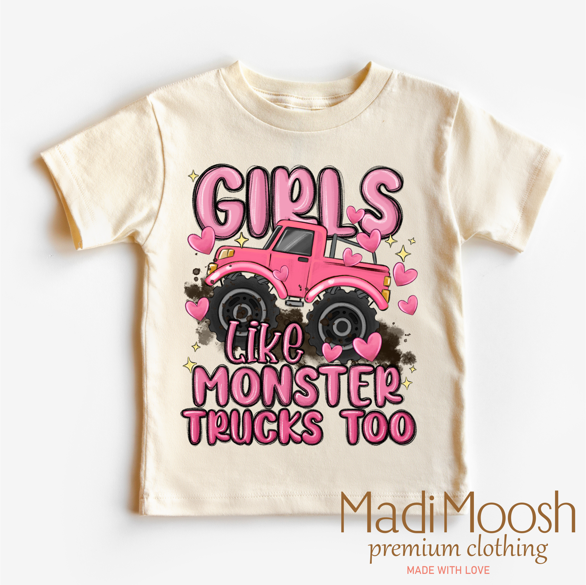 Beige t-shirt with pink monster truck graphic and text 'Girls Like Monster Trucks Too' on a white background, branded with Madi Moosh.