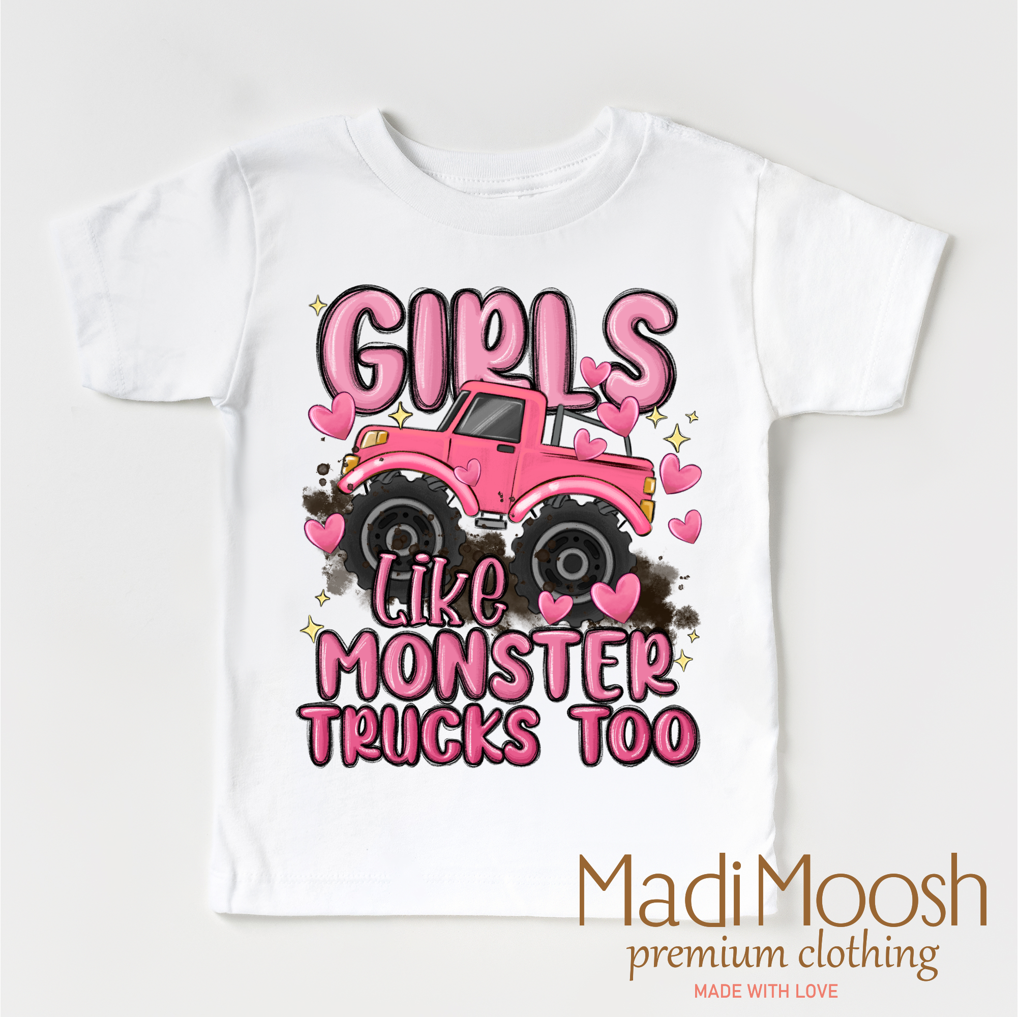 White t-shirt with pink monster truck graphic and text 'Girls Like Monster Trucks Too' on a white background, branded with Madi Moosh.
