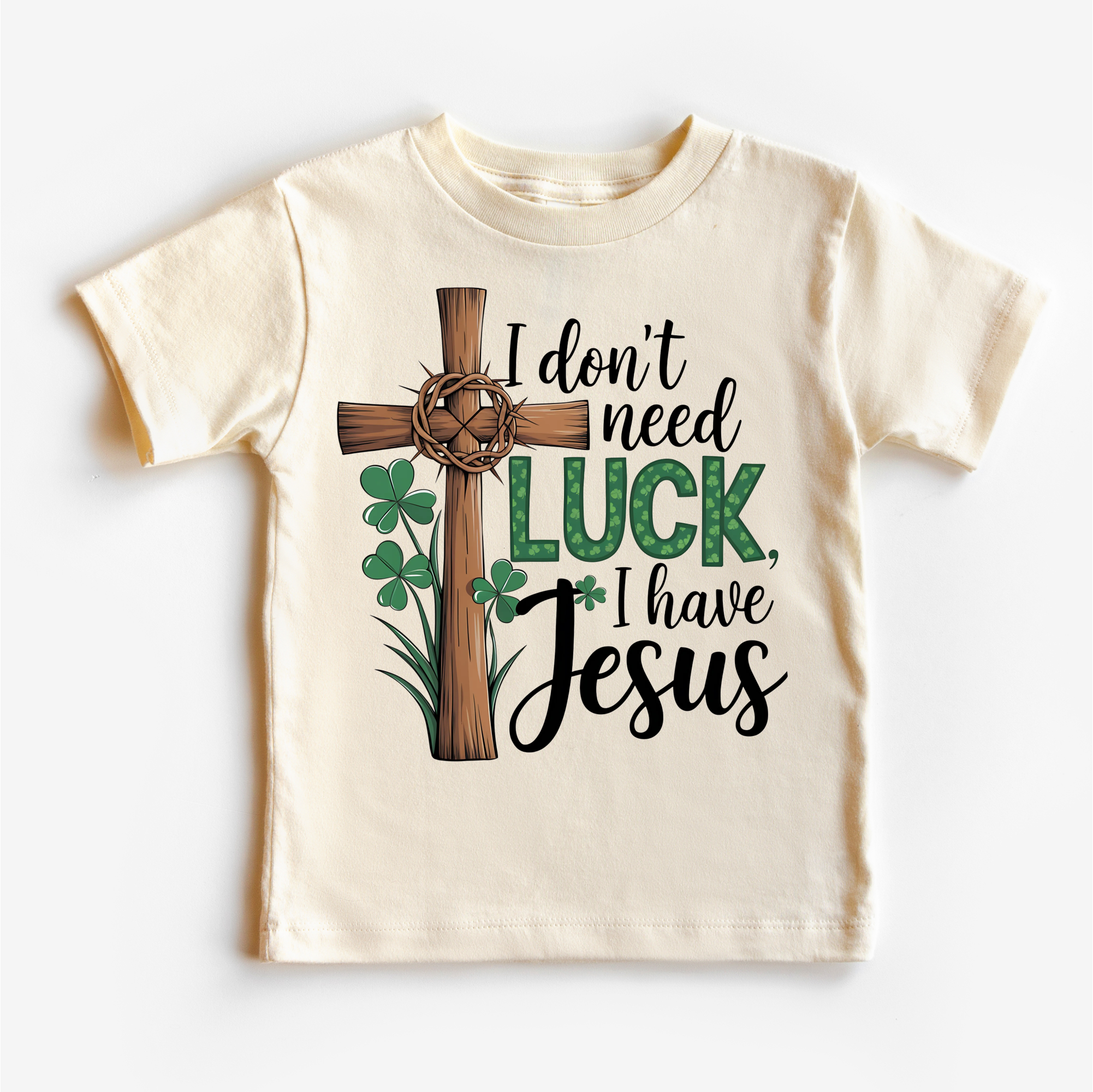 Beige t-shirt with a cross, shamrocks, and text 'I don't need luck, I have Jesus' on a white background