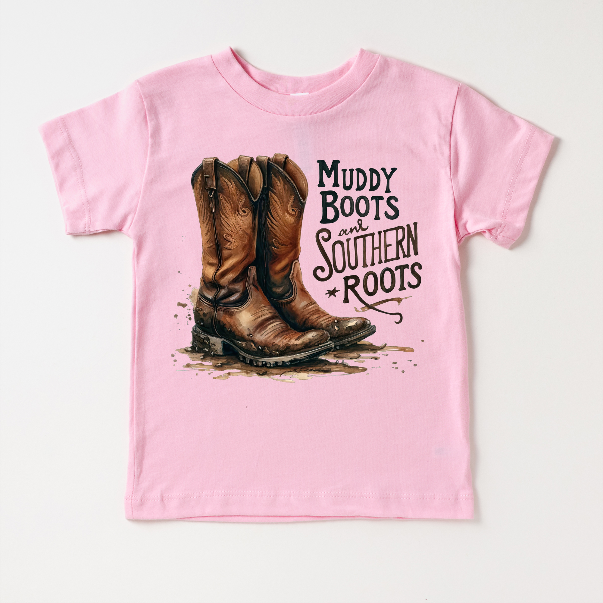 Pink t-shirt with cowboy boots and 'Muddy Boots and Southern Roots' text on a white background