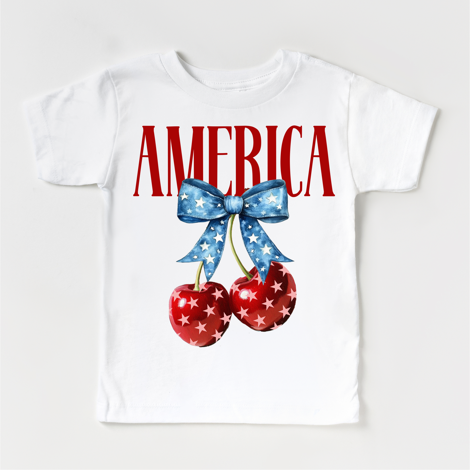 White t-shirt with 'AMERICA' text, cherries, and a bow on a white background