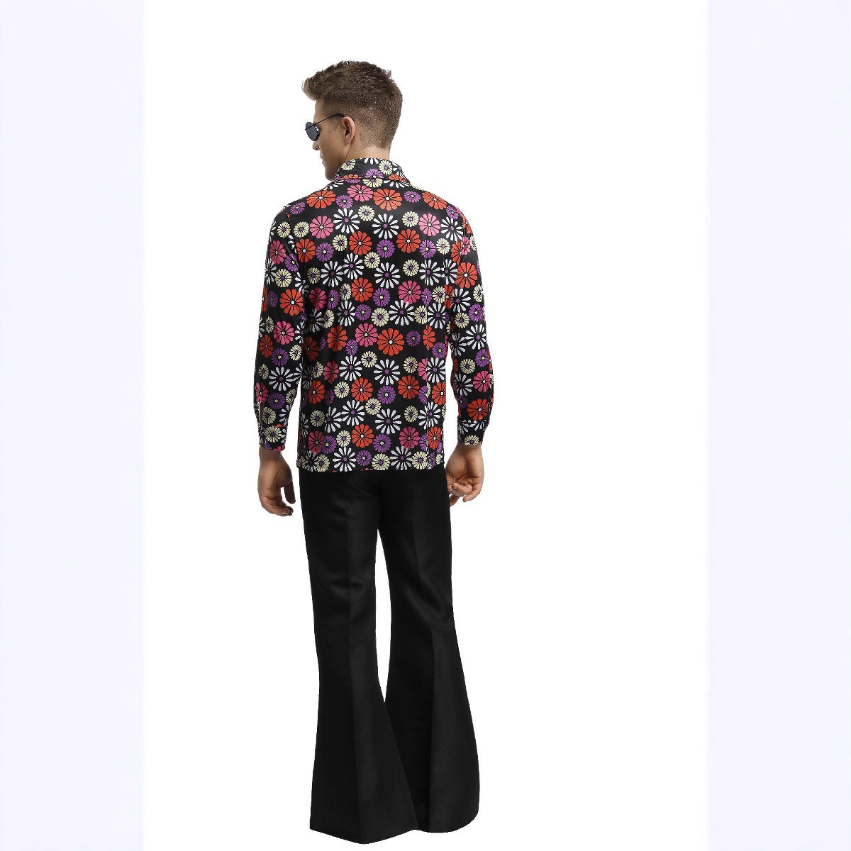 Man wearing a colorful floral shirt and black bell-bottom pants on a white background