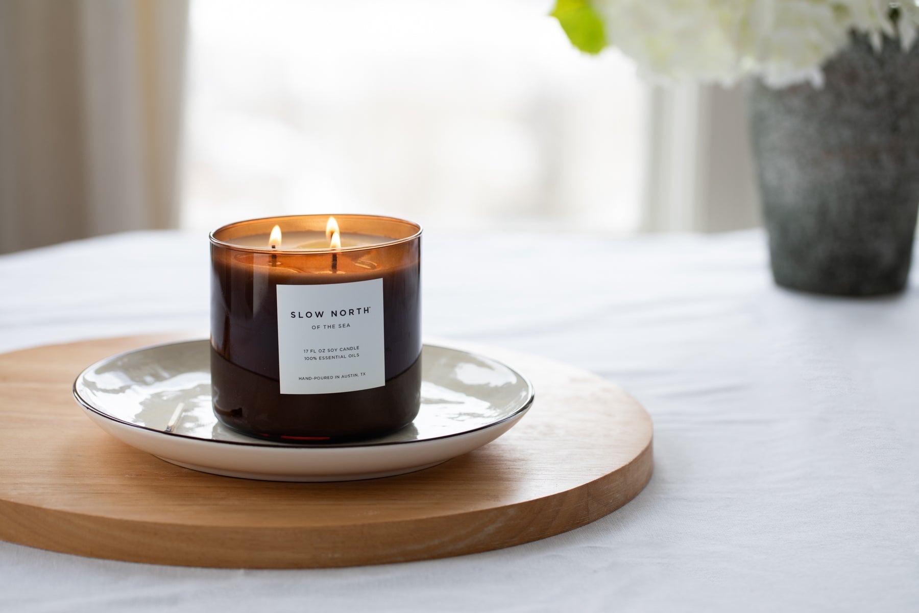 Candle with a label on a wooden tray on a table