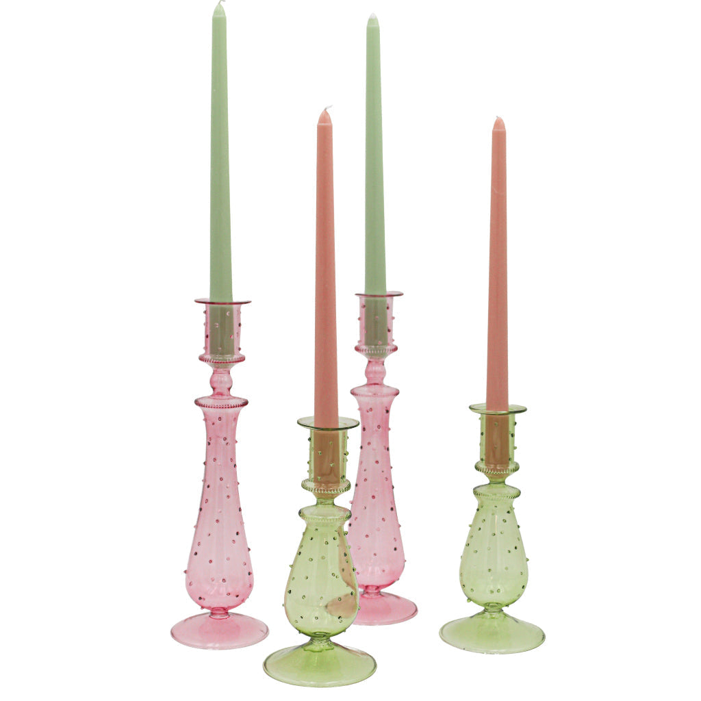 Set of four pastel-colored candlesticks with candles on a white background