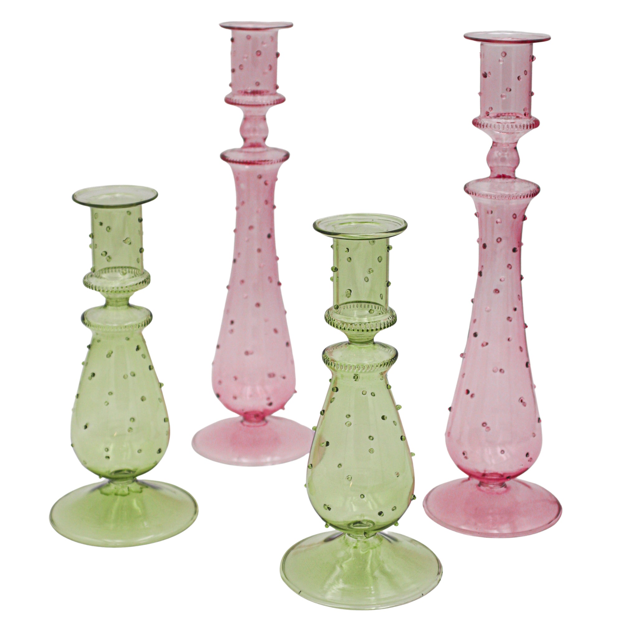 Set of four glass candlesticks in pink and green on a white background