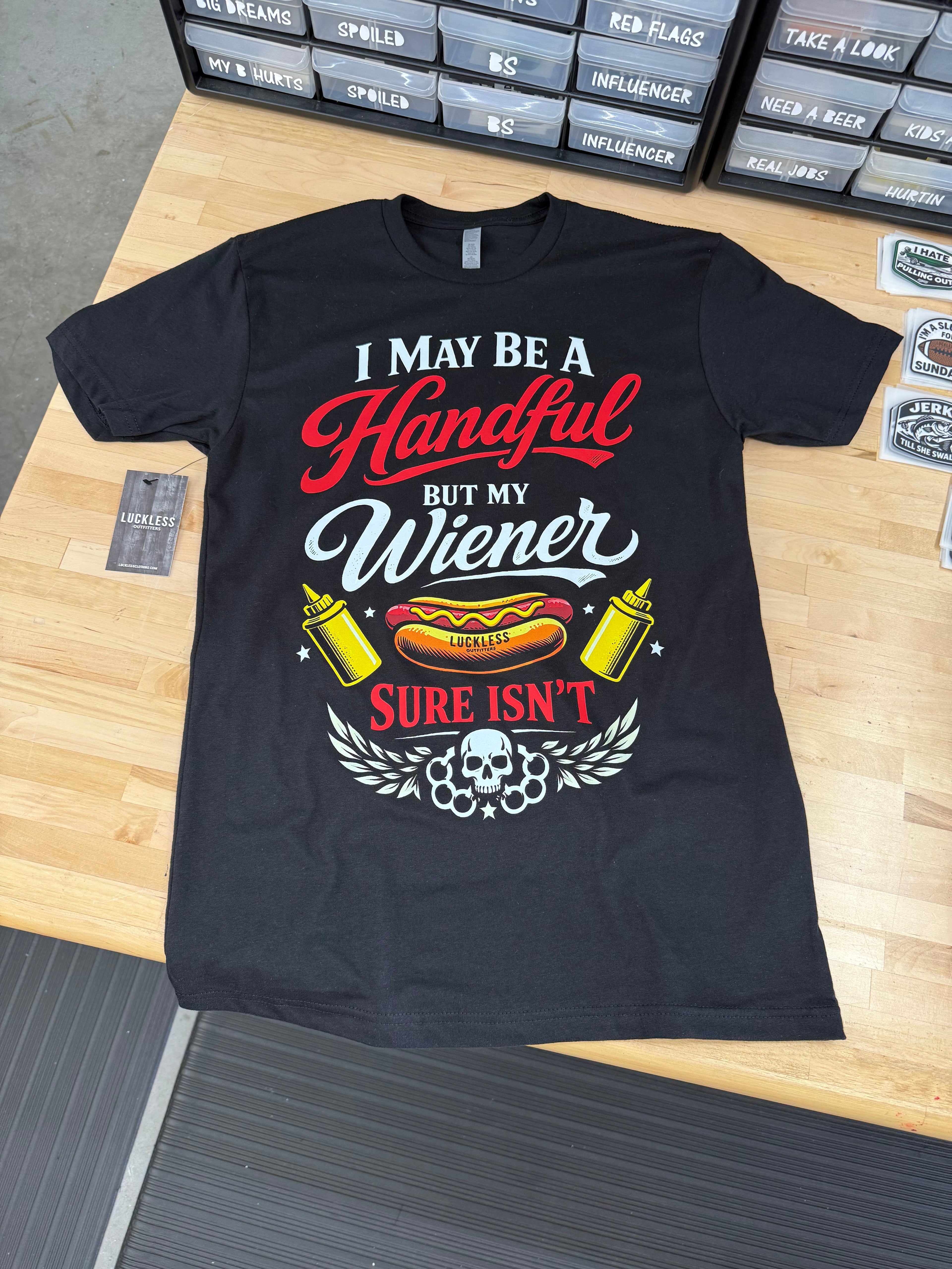 Black t-shirt with humorous graphic design on a wooden surface