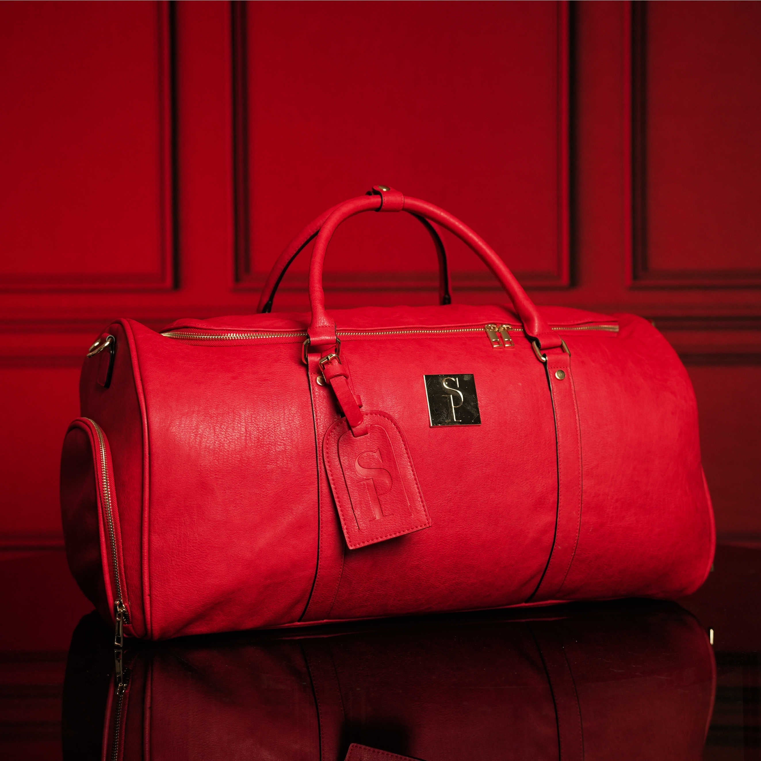 Red leather duffel bag with a visible brand logo on a red background