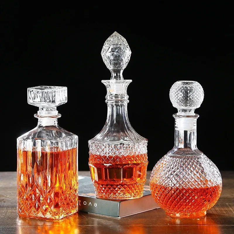 Three crystal decanters with different stopper designs on a wooden surface.