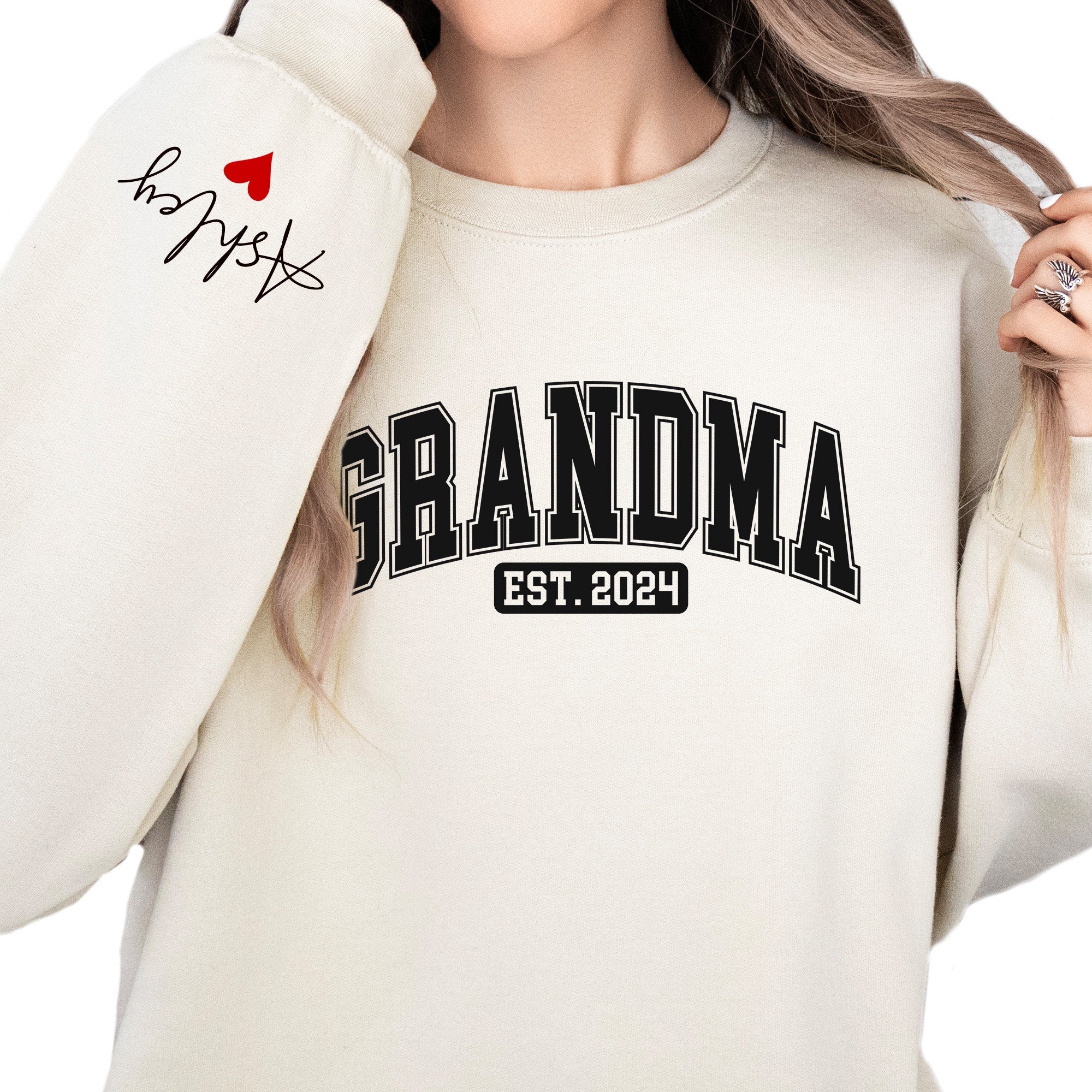 White sweatshirt with 'GRANDMA EST. 2024' text, worn by a person.