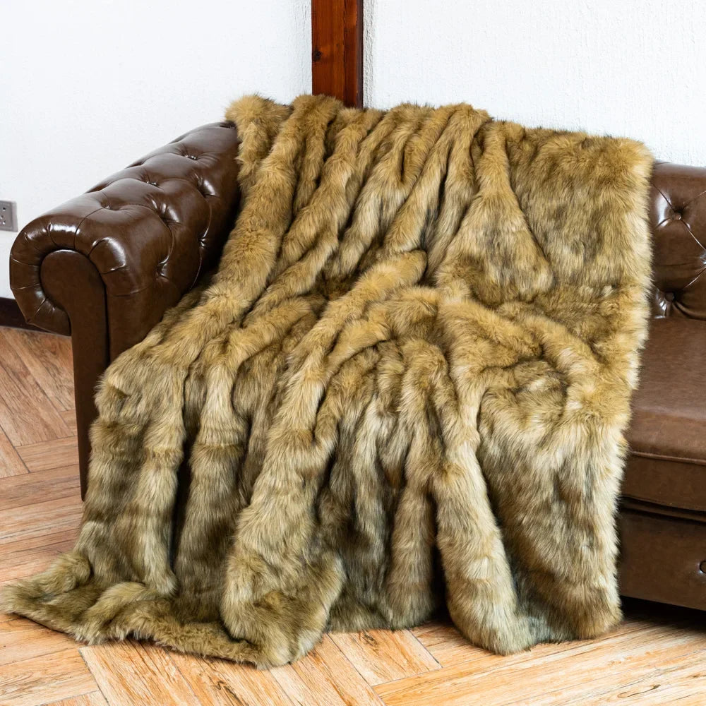 Brown fur throw blanket draped over a brown leather sofa.