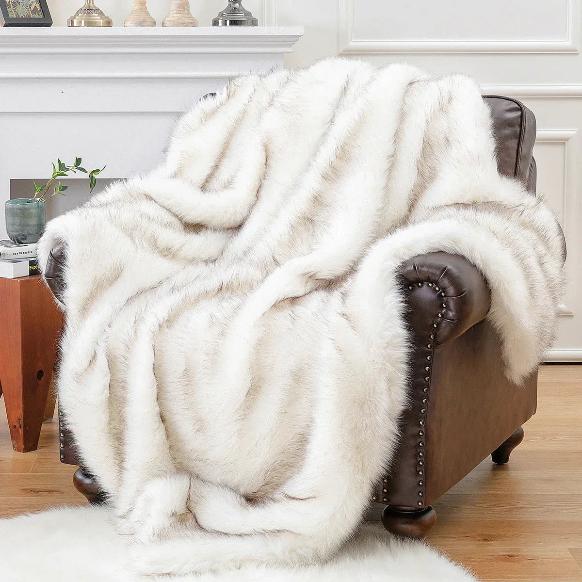 White fur throw blanket draped over a brown leather armchair in a living room setting.