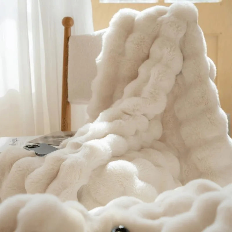 White fluffy blanket draped over a chair in a softly lit room.
