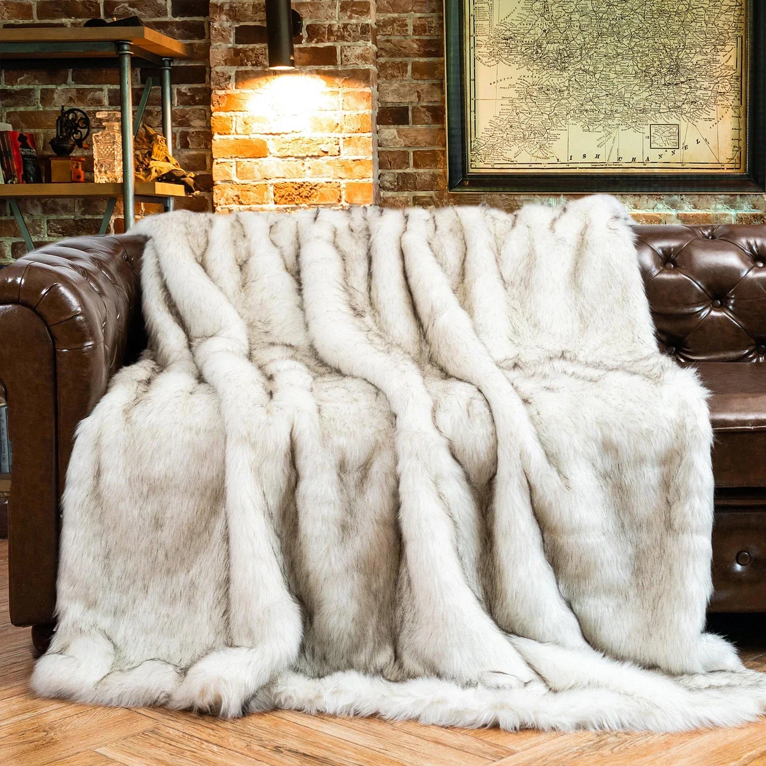 White fur throw blanket draped over a brown leather sofa in a cozy living room.