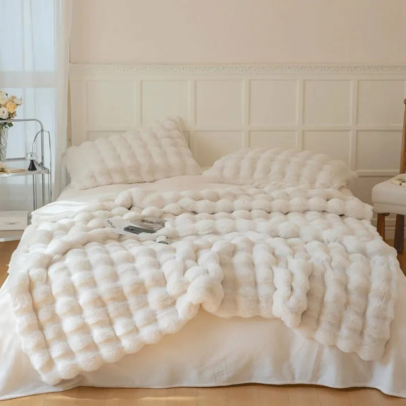 White fluffy blanket draped over a bed in a bedroom setting