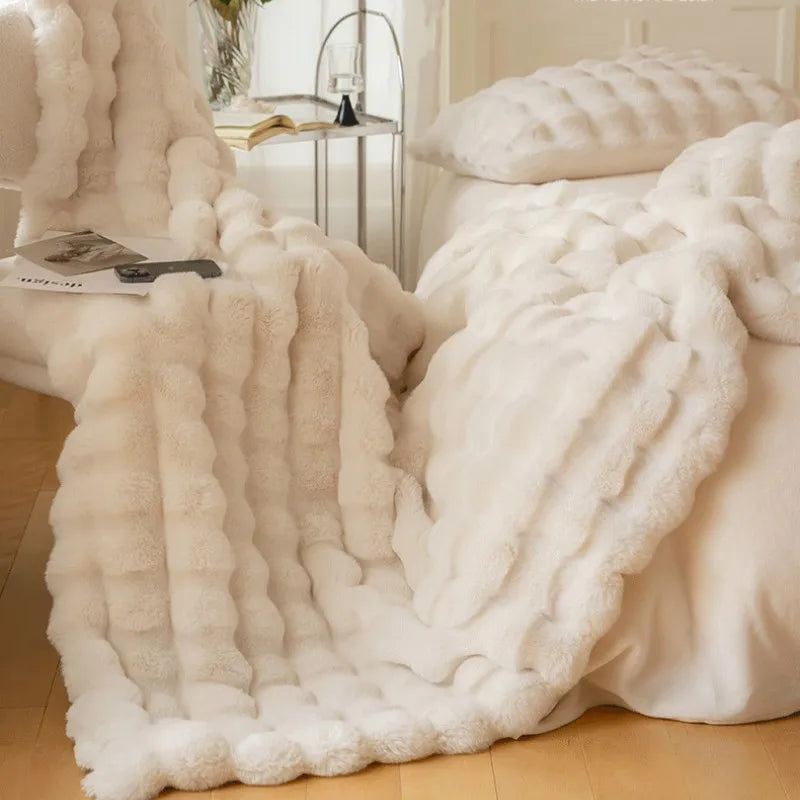 Fluffy white blanket draped over a bed in a bedroom setting.